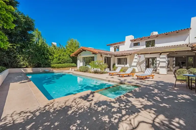 a-pool-and-some-chairs-near-a-house-with-a-patio