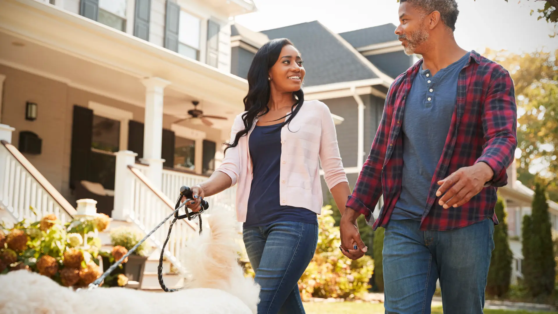 Couple Walking Dog Along Suburban Street