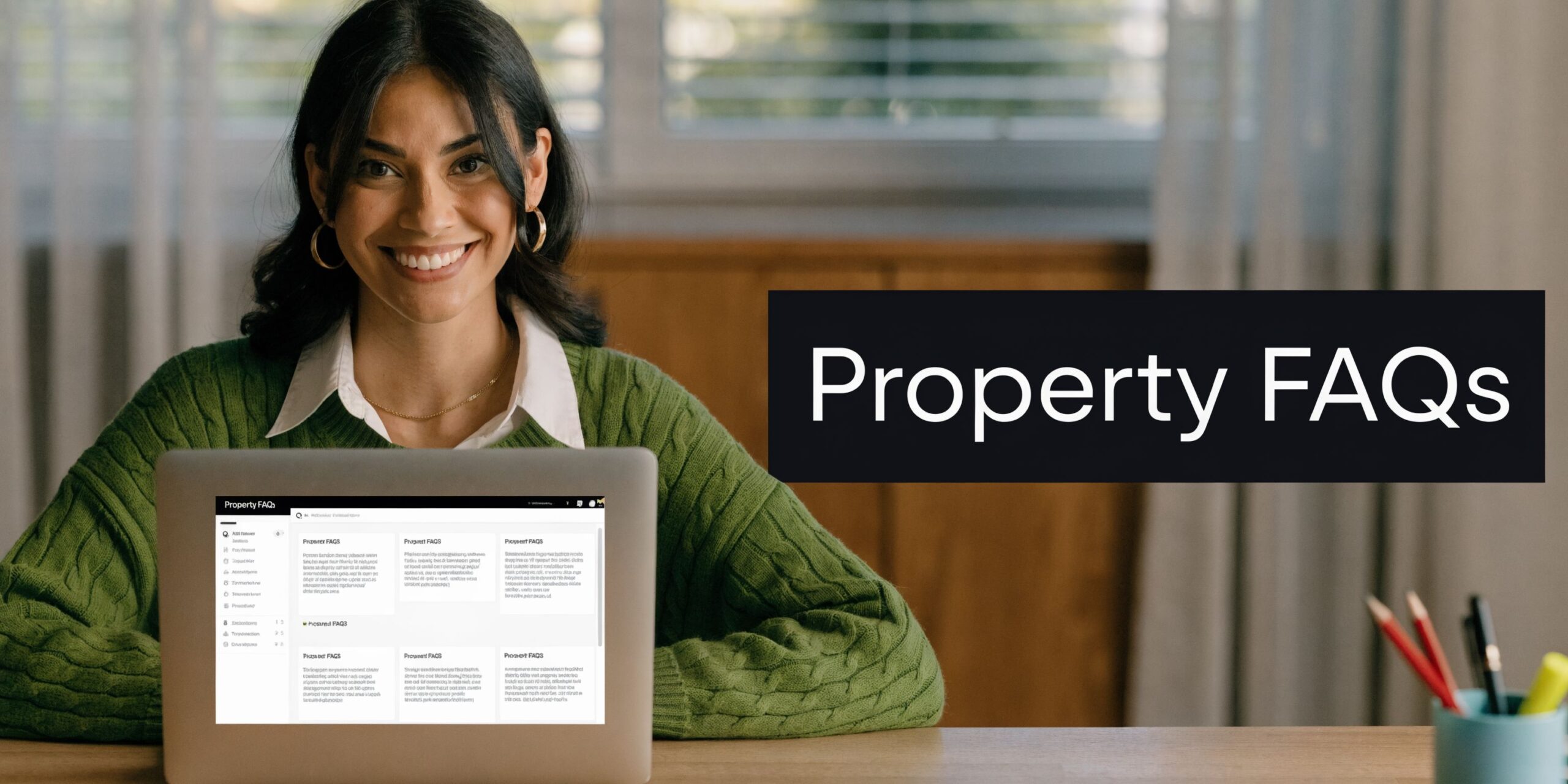 A smiling woman in a green sweater works on a laptop displaying Property FAQs at her desk.